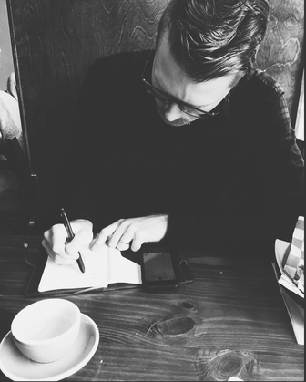 Matthew Palmer writing in a journal at a Pinewood Coffee House.